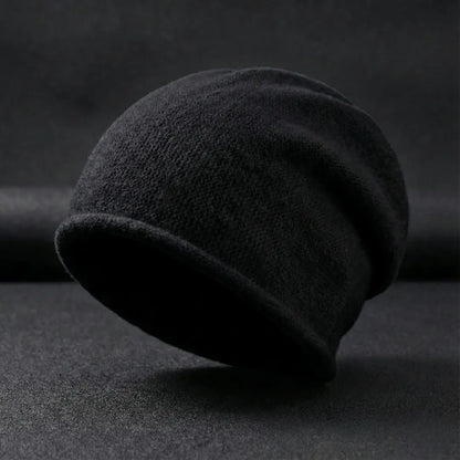 Dark gray beanie on a textured black surface with a dark background