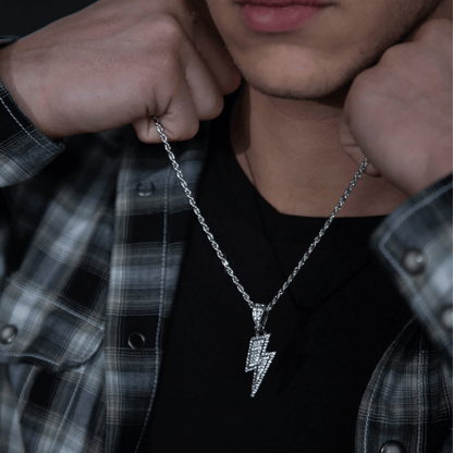 Person wearing a silver necklace with a lightning bolt pendant, plaid shirt partially visible