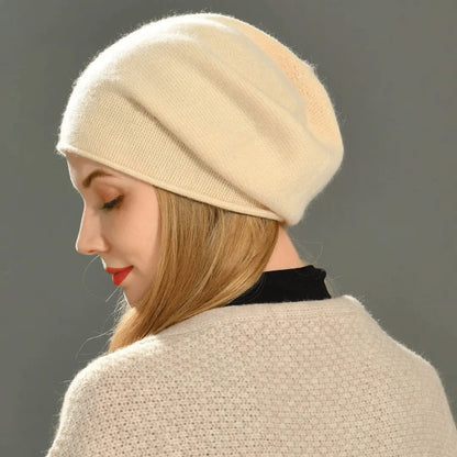 Woman wearing a beige beanie and coat against a gray background