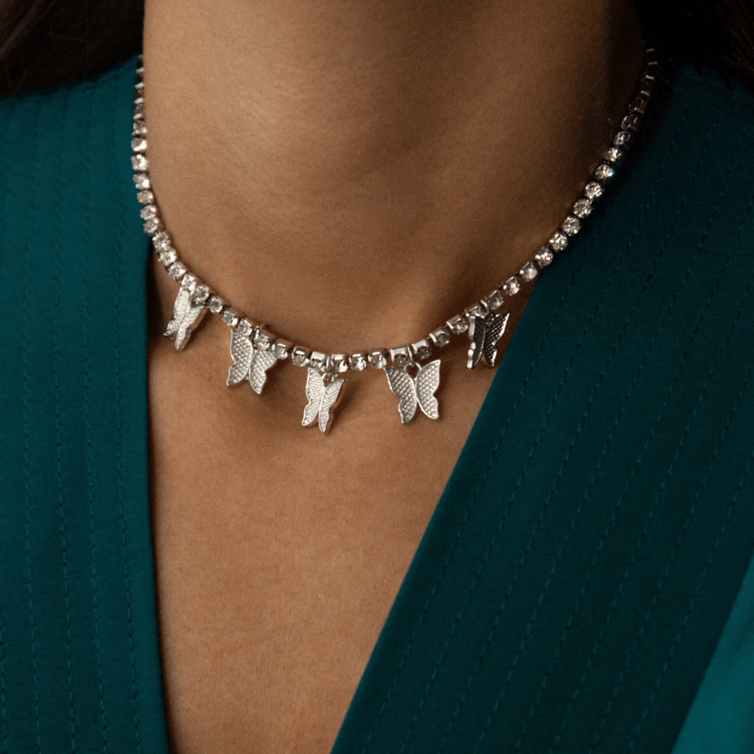 Necklace with butterfly charms worn by a person against a teal background