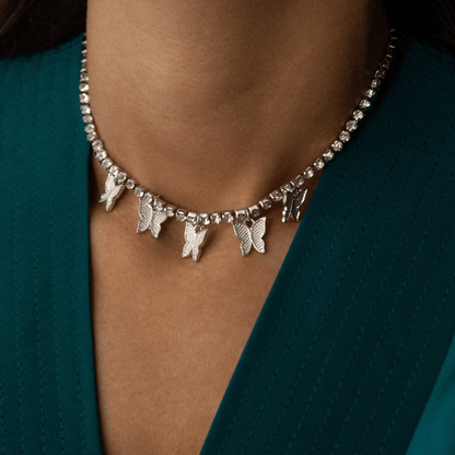 Necklace with butterfly charms worn by a person against a teal background