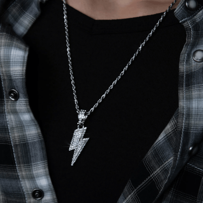 Person wearing a black shirt with a silver lightning bolt necklace and plaid jacket.