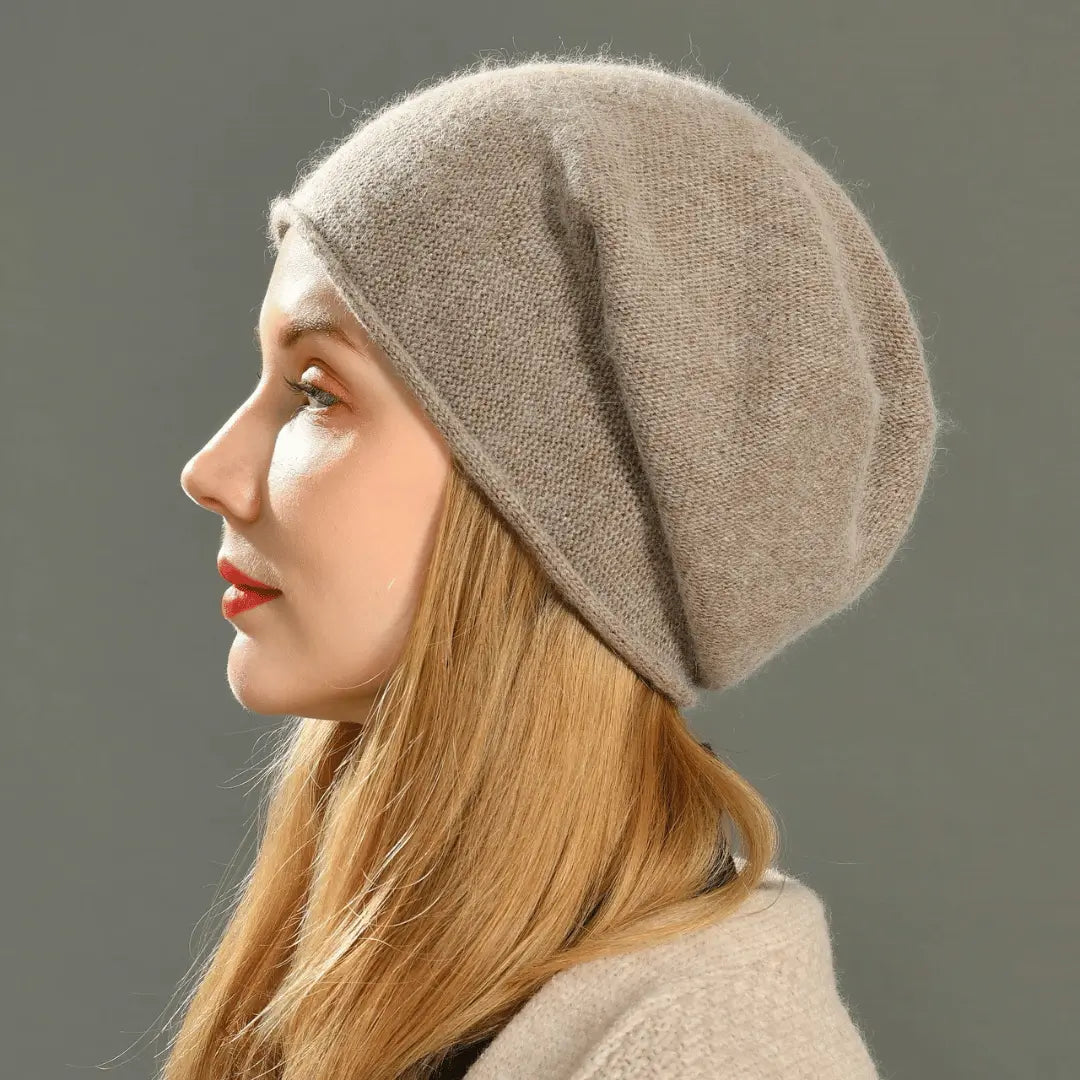 Woman wearing a beige knit beanie against a gray background