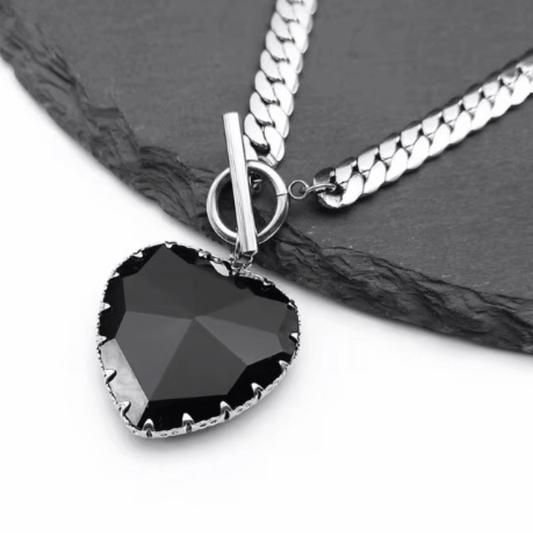 Necklace with a black heart-shaped pendant on a dark surface