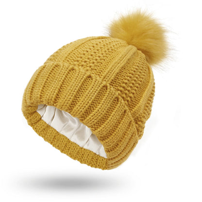 Yellow knit beanie with a pom-pom on a white background