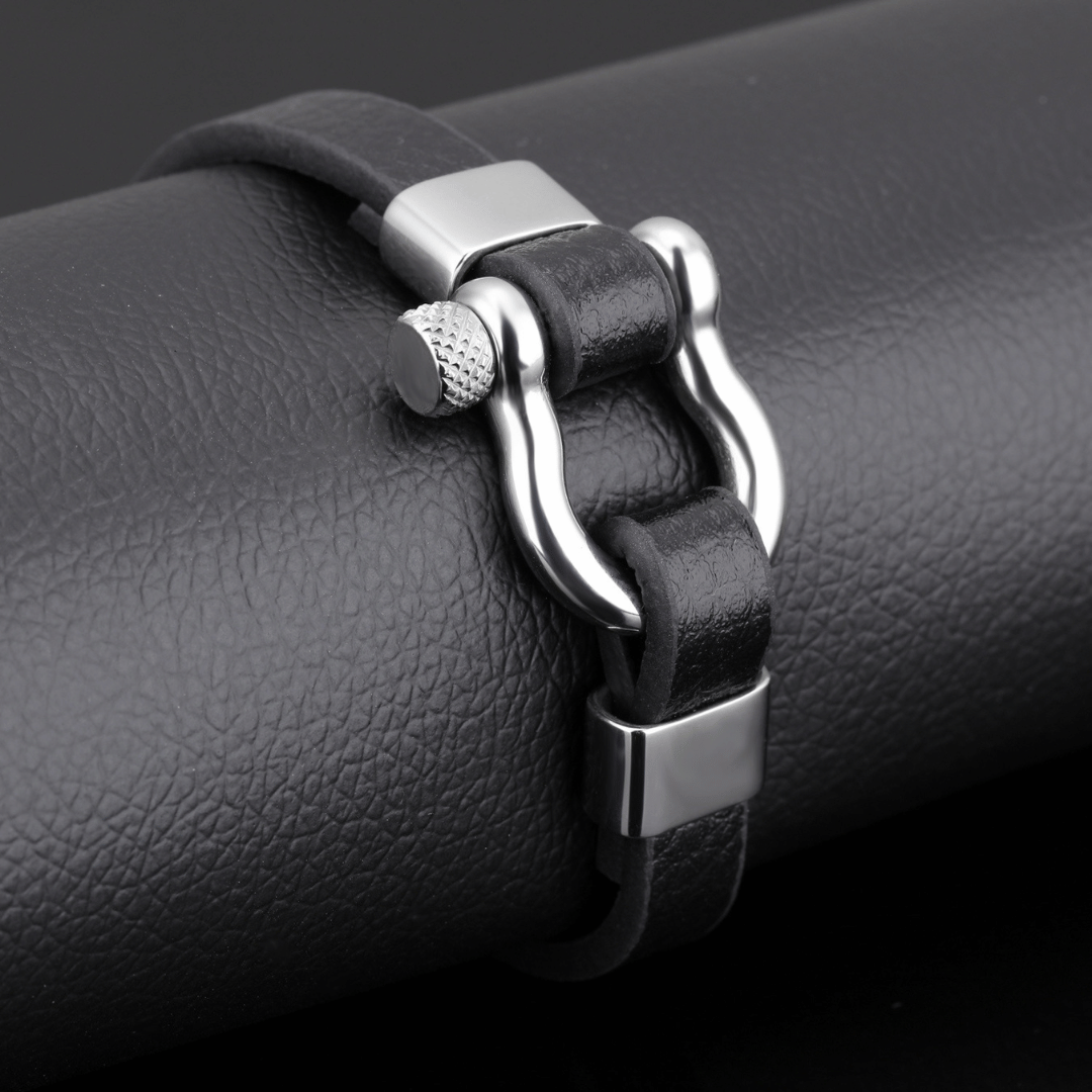 Black leather bracelet with silver clasp on a black surface