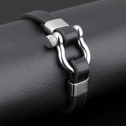 Black leather bracelet with silver clasp on a black surface