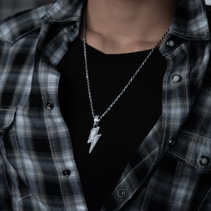 Person wearing a black shirt and plaid jacket with a silver necklace featuring a lightning bolt pendant.