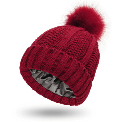 Red knitted beanie with a pom-pom on a white background