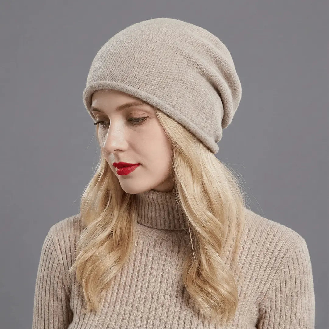 Woman wearing a beige knit hat and sweater against a gray background