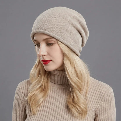 Woman wearing a beige knit hat and sweater against a gray background