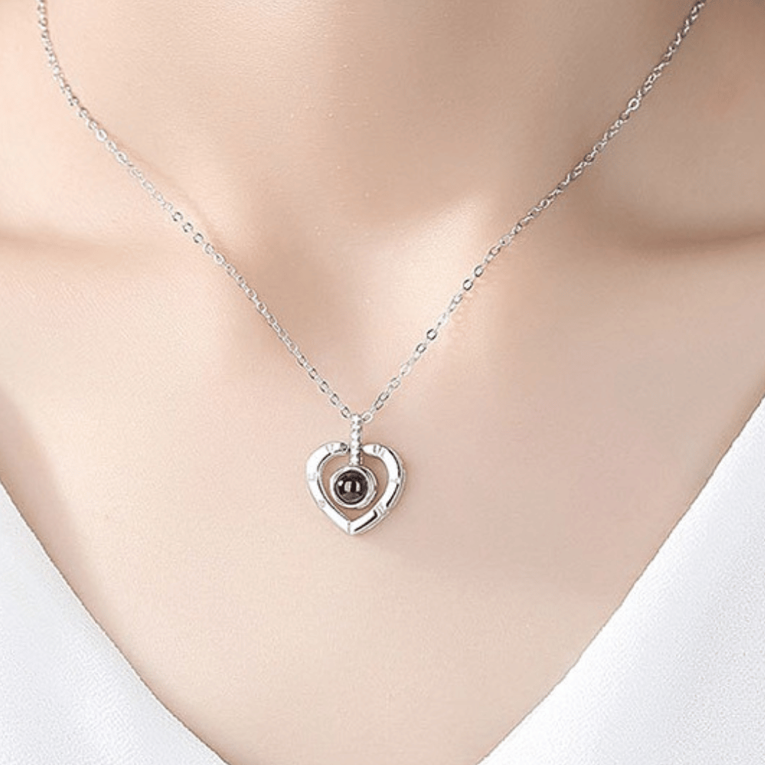 Silver heart-shaped necklace with a dark pendant on a mannequin.