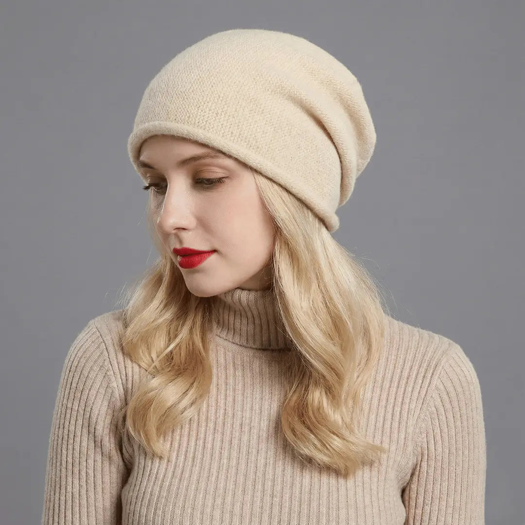 Woman wearing a beige knit hat and sweater against a gray background