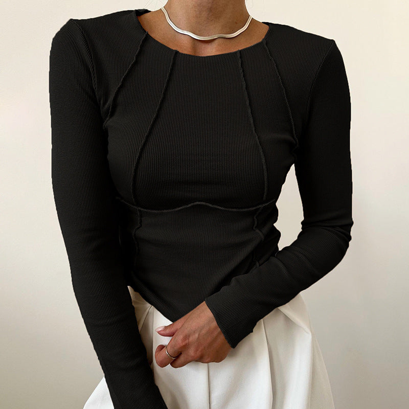 Person wearing a black long-sleeve top with a plain background