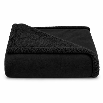 A folded black fleece blanket with a plush sherpa lining, shown on a clean white background.