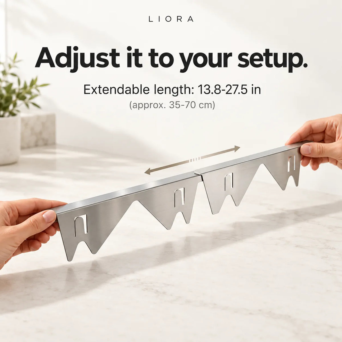 Hands holding a stainless steel extendable shelf divider on a light marble countertop, with text above reading 'Adjust it to your setup. Extendable length: 13.